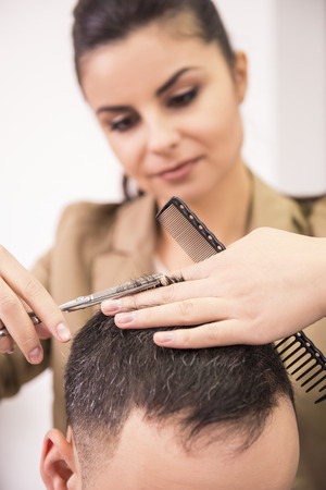 Female hairdresser is cutting hair of man client.の写真素材