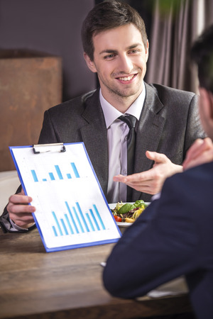 Rear view. Businessmen analyzing graphs during a business lunch.の写真素材