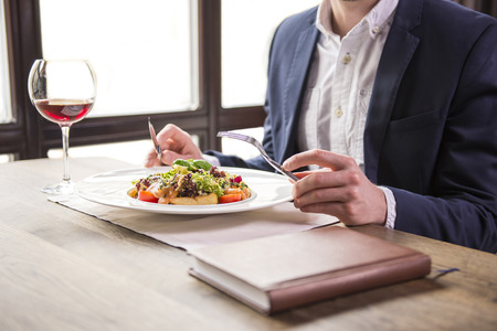 Close-up. Businessman eating during a business lunch in restaurant.の写真素材