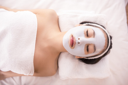 Spa therapy for young asian woman receiving facial mask at beauty salon.の写真素材