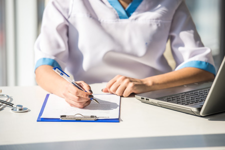 Doctor at work, close up of female doctor typing on a computer.の写真素材