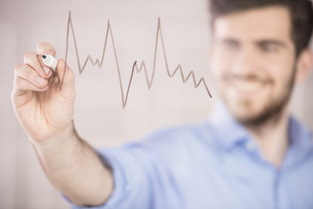 Young handsome businessman drawing on glass screen in office.の写真素材