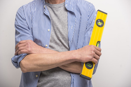 Close-up. Builder holding building level on grey background.