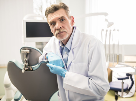 Portrait of a smiling senior dentist in dental clinic.の写真素材