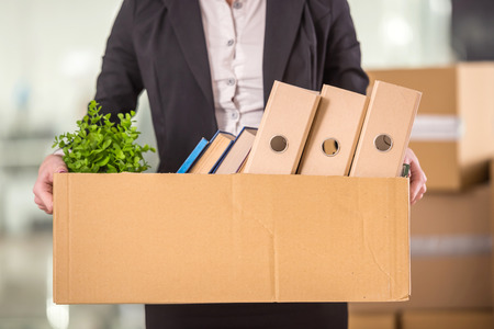 Close-up. Smiling young businesswoman holding cardboard box with her things.の写真素材