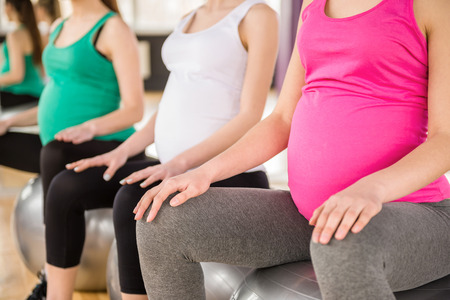 Fitness, sport and lifestyle concept - three pregnant women with exercise balls in gym.の写真素材