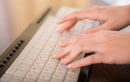 Close-up of hands typing on laptop keyboard in the office.の写真素材