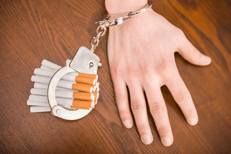 Man hand with handcuffs and cigarettes on the table. The concept of smoking dependence.の写真素材
