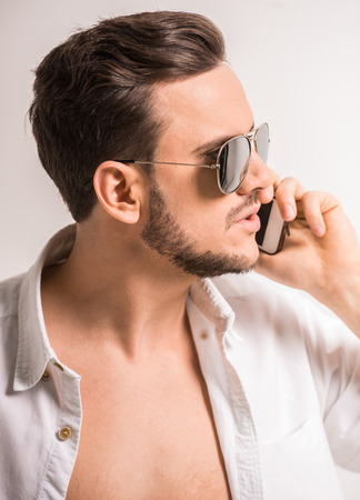 Side view of young man in glasses and shirt is talking by phone.の写真素材