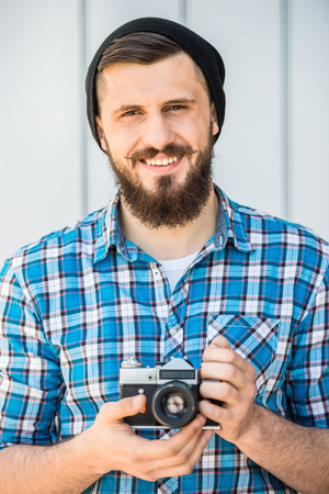 Young bearded man with vintage camera is making a picture.の写真素材