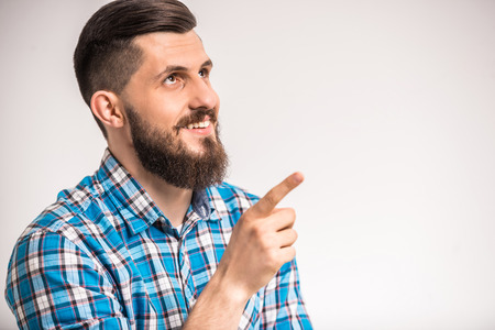 Side view of  young smiling man with beard is pointing on something.の写真素材