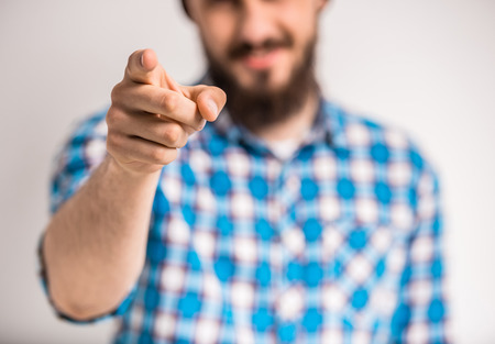 Handsome bearded man is pointing on you. Gray background. Focus on finger.の写真素材