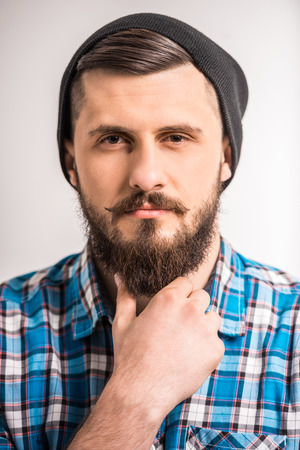 Close-up of young confident man with hand in beard.の写真素材