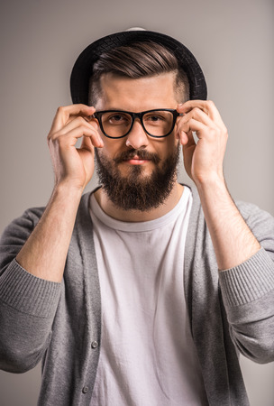 Bearded man in hat and glasses on gray background.の写真素材
