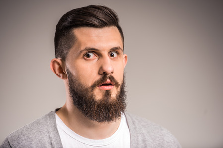 Shocked bearded man on gray background is looking at the camera.の写真素材