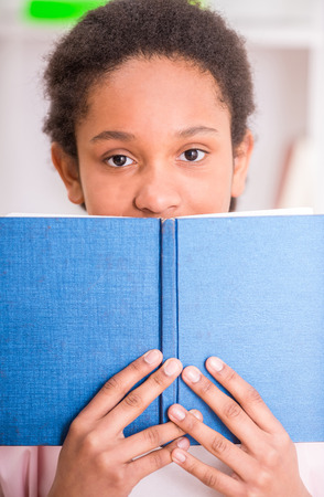 Young pretty mulatto schoolgirl holding a book in hands.の写真素材