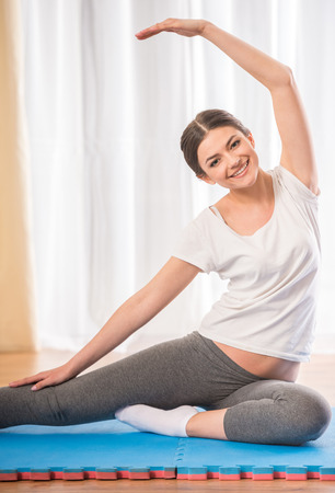 Young pretty athletic girl doing yoga on a rug at home.の写真素材