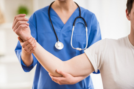 Close-up of female doctor  stretching arm to male patient.の写真素材