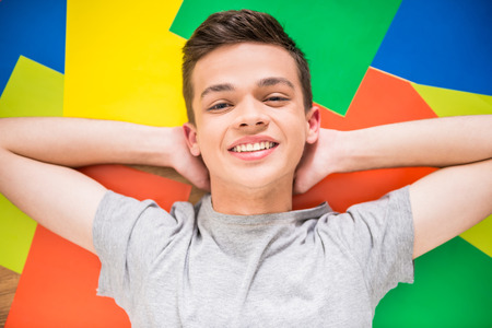 Image of teenager lying on the colorful floor, smiling and looking at the camera.の写真素材