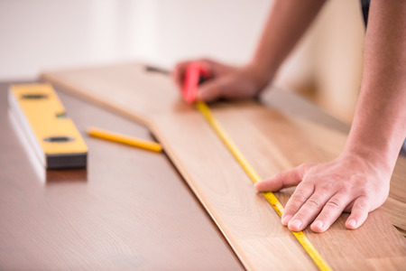 Close-up of carpenter measuring wooden plank. House renovation service.の写真素材