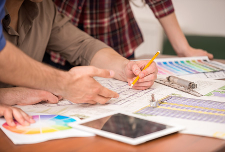 Close-up of three young creative designers working on project together. Team work.