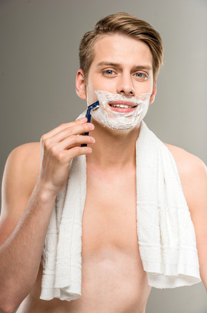 Handsome man with towel on shoulders shaving after bath.の写真素材