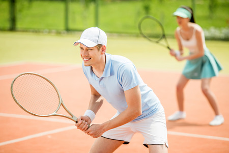 Couple playing doubles at the tennis court. Healthy lifestyle concept.の写真素材