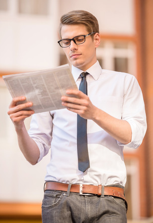 Young office worker reading newspaper in the morning outdoors.の写真素材