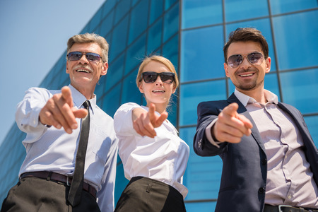 Three successful business people in suits posing to camera outdoors. Office background.の写真素材
