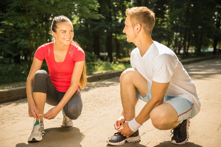 Young sporty couple prepares to run sprint. Training outdoors at sunrise.の写真素材
