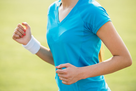 Close-up of woman running outdoors at sunrise. Wellness and health concept.