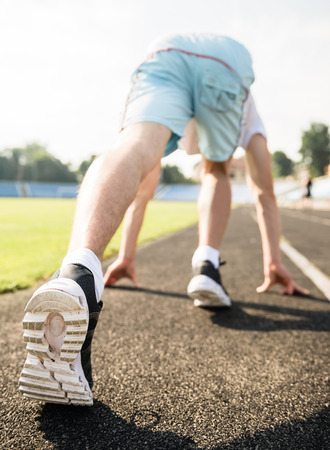 Closeup of sporty man ready to run sprint. Male athlete in powerful starting line pose.の写真素材