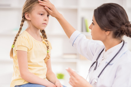 Young female pediatrician measuring temperature to her little patient.の写真素材