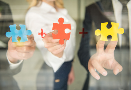 Image of confident business people wanting to put pieces of puzzle together. Close-up.