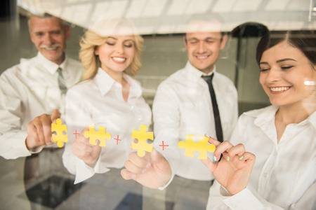 Group of business people assembling jigsaw puzzle and represent team support and help concept.の写真素材