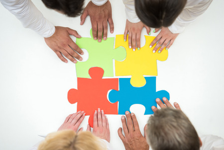 Group of business people assembling jigsaw puzzle and represent team support and help concept....
