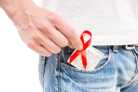 Healthcare and medicine concept - man with red AIDS awareness ribbon with condom in hand.の写真素材