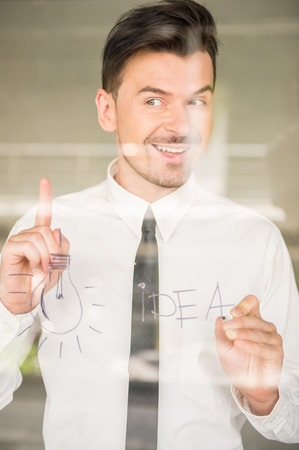 Successful business man drawing an idea on glass window at office.の写真素材