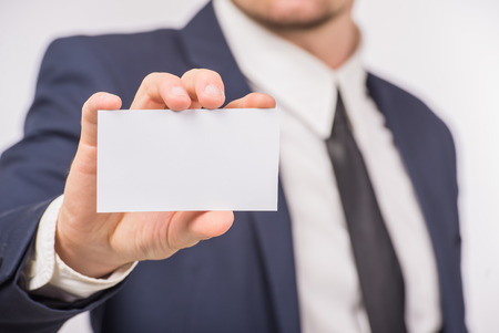 Business man handing a blank business card over white background.