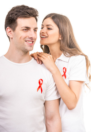 Young attractive couple supporting aids awareness together on white background.の写真素材