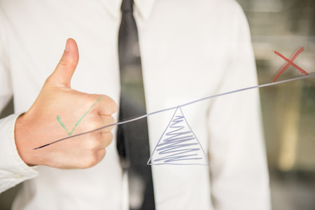 Young business man writing success diagram on glass board with marker.の写真素材