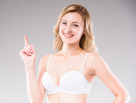Beautiful blonde in white casual bra looking at camera, gray background. Studio shoot.の写真素材