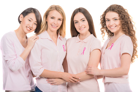 Voluntary cheerful women wearing pink ribbons to support breast cancer campaign, white background.の写真素材