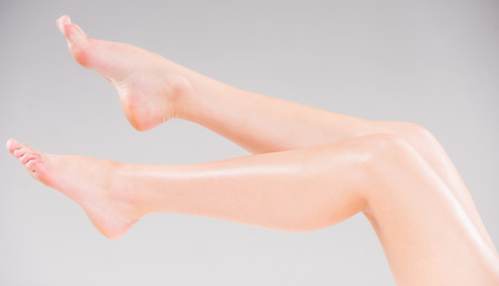 Beautiful woman's legs over gray background. Studio shoot.の写真素材