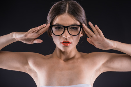 Piercing glance. Confident young shirtless woman looking at camera while standing against black background.の写真素材