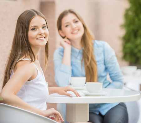 Two beautiful young women meeting for coffee at urban cafe in summer.の写真素材