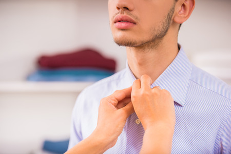Woman's hands buttoning shirt on her boyfriend. Close-up.の写真素材