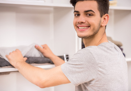 Portrait of young man choosing clothes in the wardrobe and smiling at camera.の写真素材