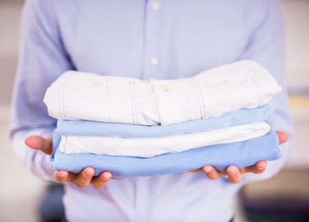 Young man holding clothes in his hands. Close-up.の写真素材