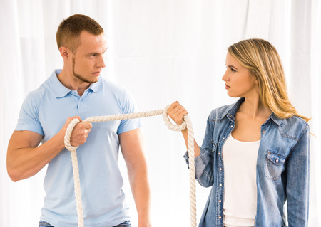 Young couple having big trouble in relations, they pulling rope to each other.の写真素材